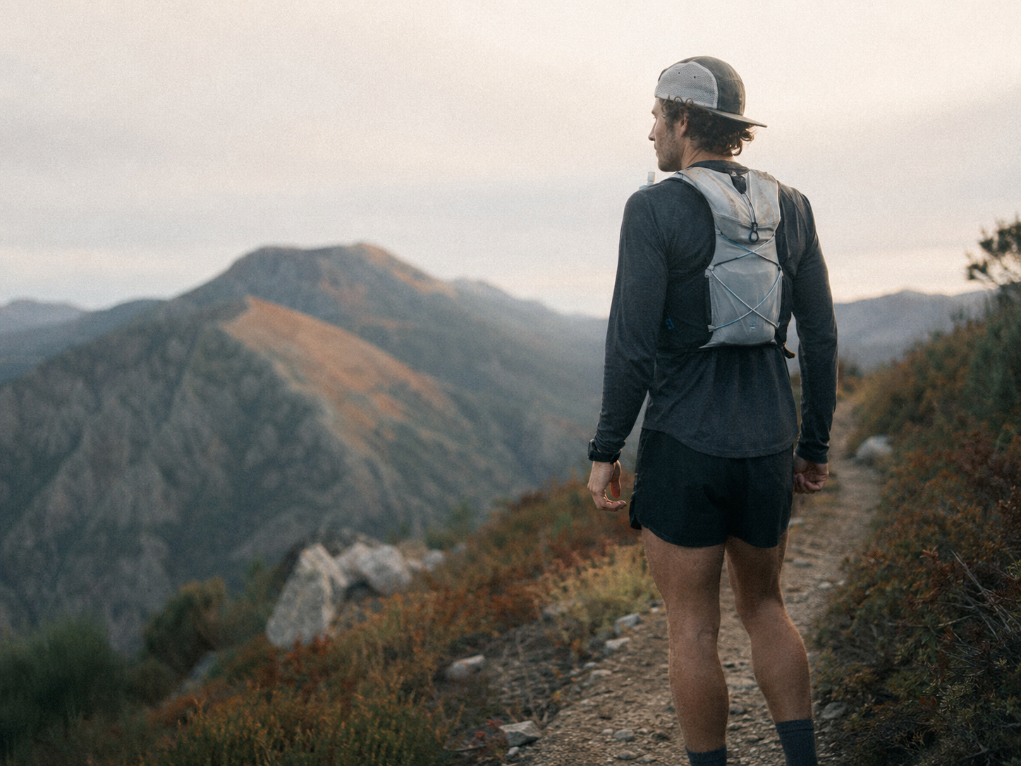 Trail runner alone facing the mountains at sunset
